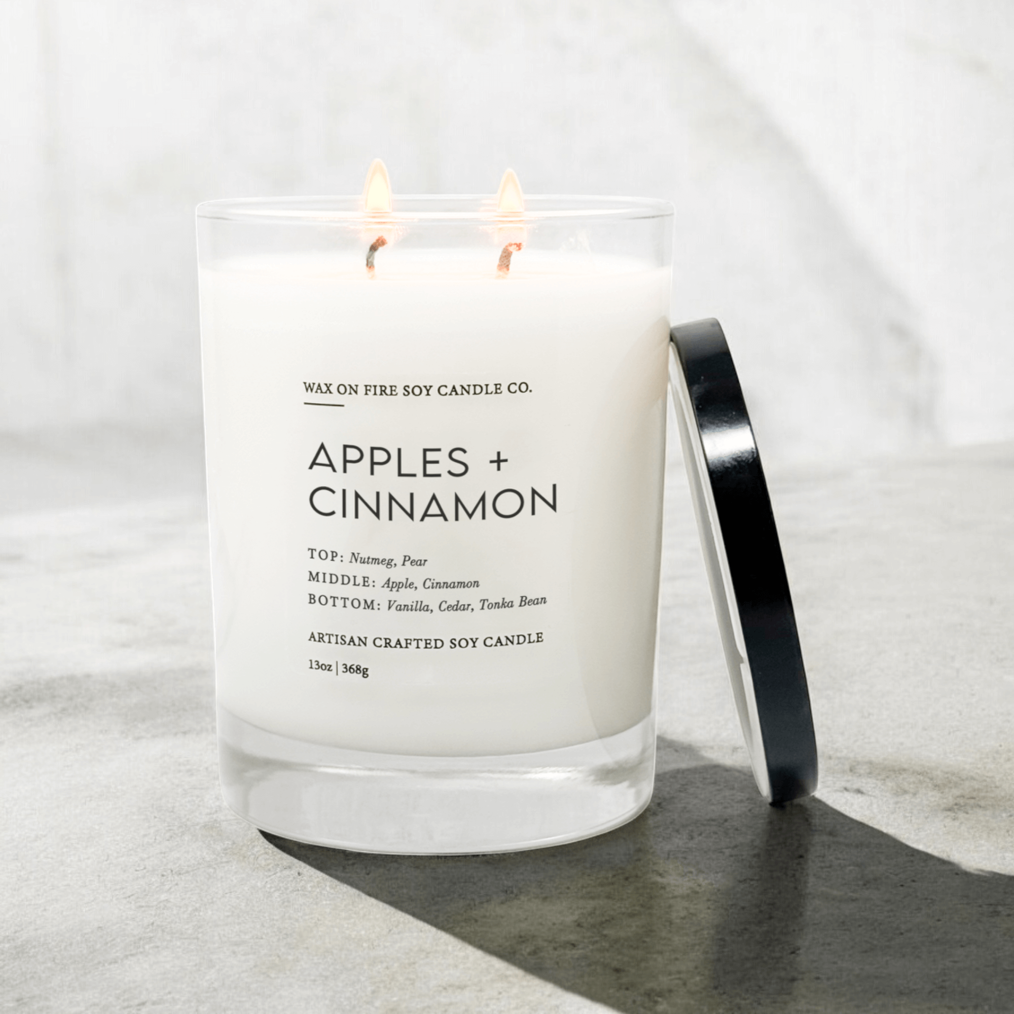 Apples + Cinnamon Luxe 2-Wick Candle in clear glass jar, featuring nutmeg, apple, and vanilla scents.