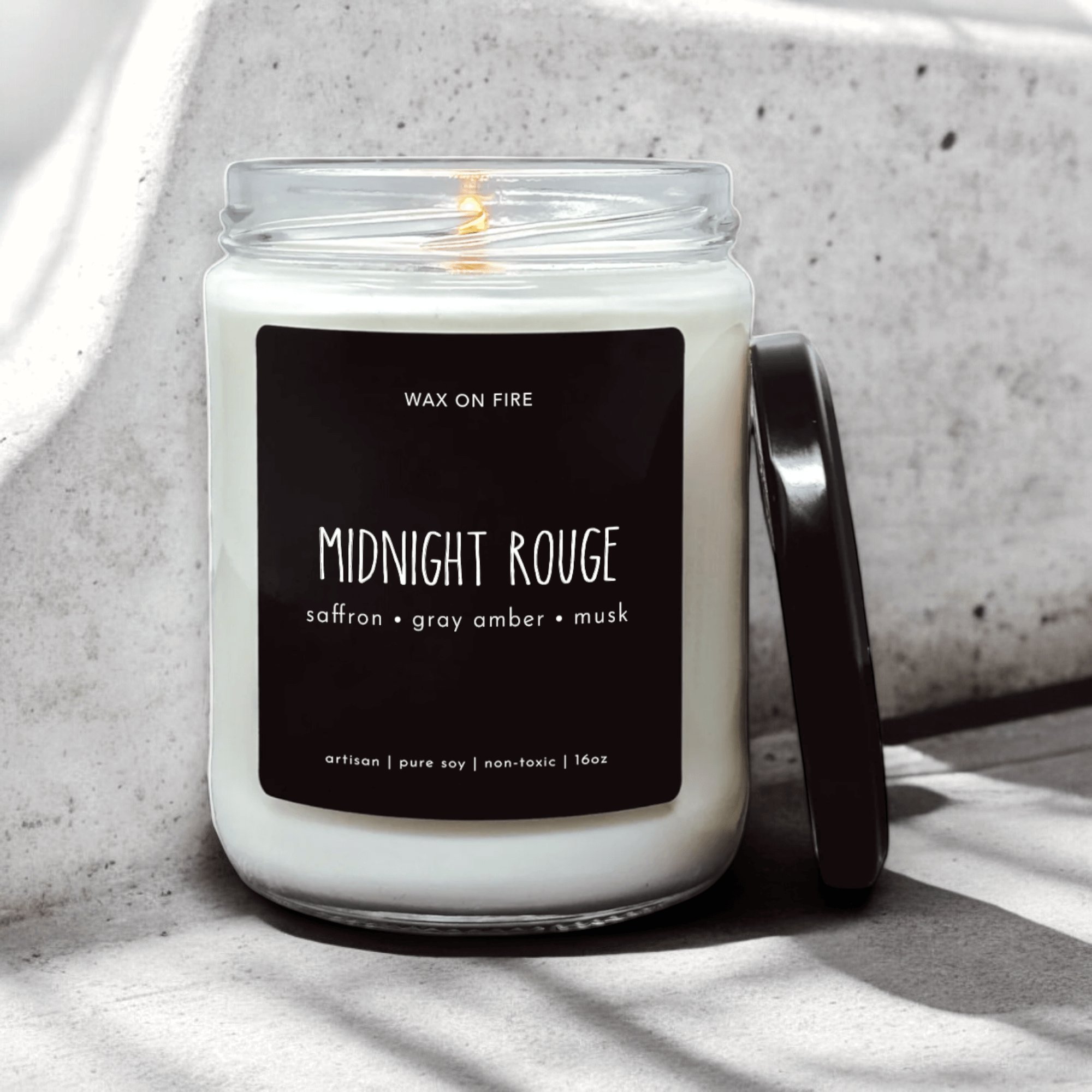 Midnight Rouge candle with saffron, gray amber, and musk notes in a sleek glass container.