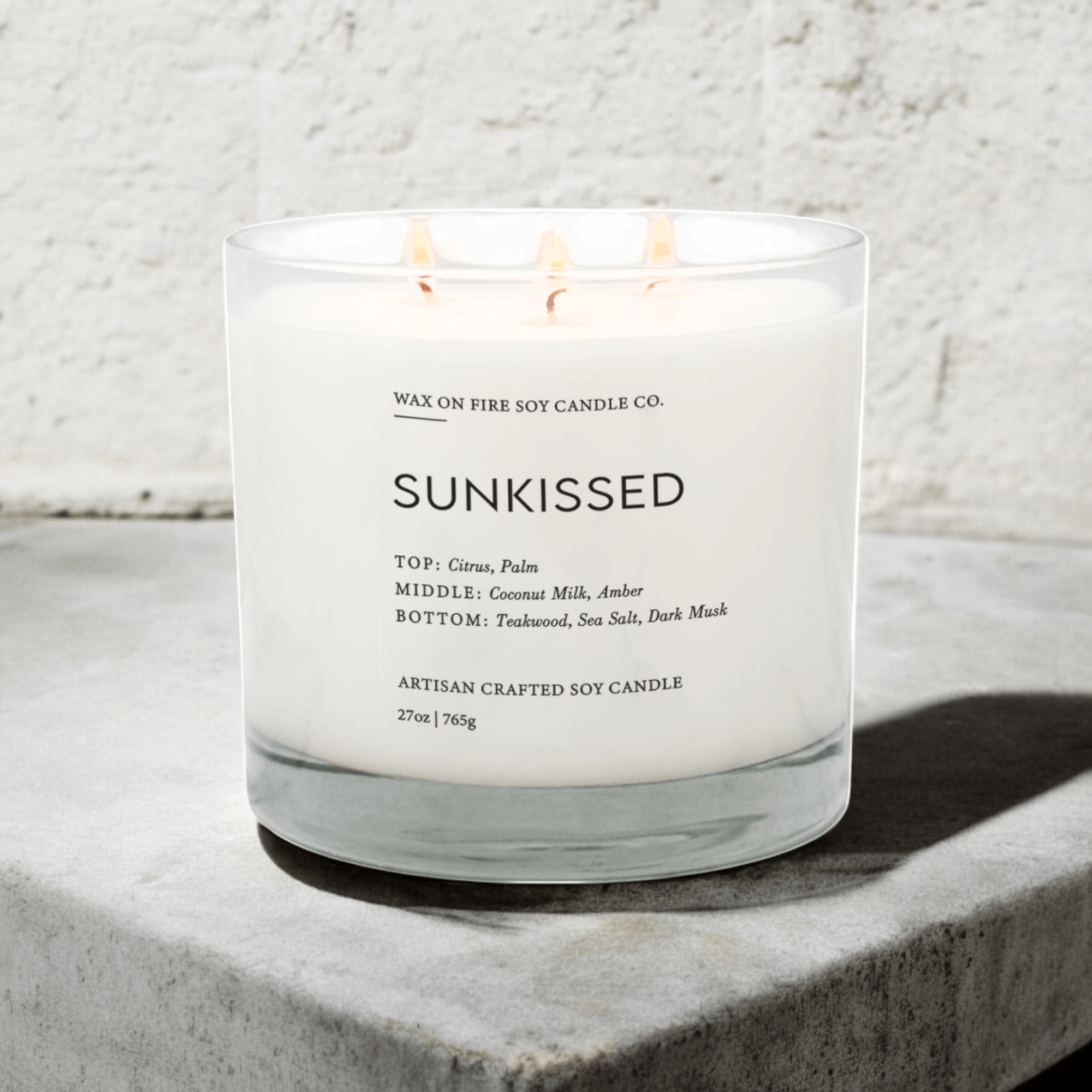 Sunkissed luxe 3-wick soy candle with citrus, coconut milk, and teakwood scent notes on a stone surface.