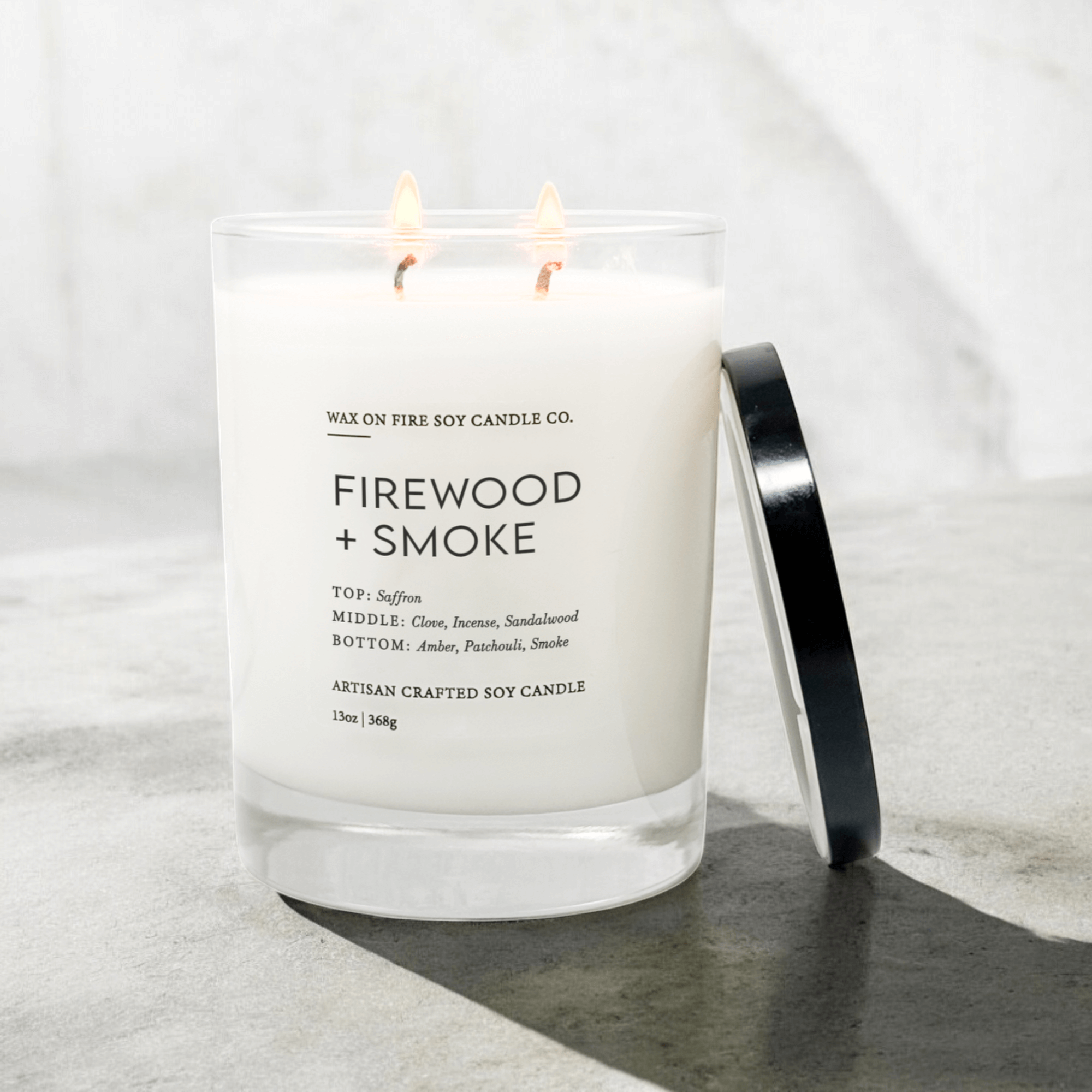Firewood + Smoke 2-wick candle with saffron, clove, and amber notes in a glass container.