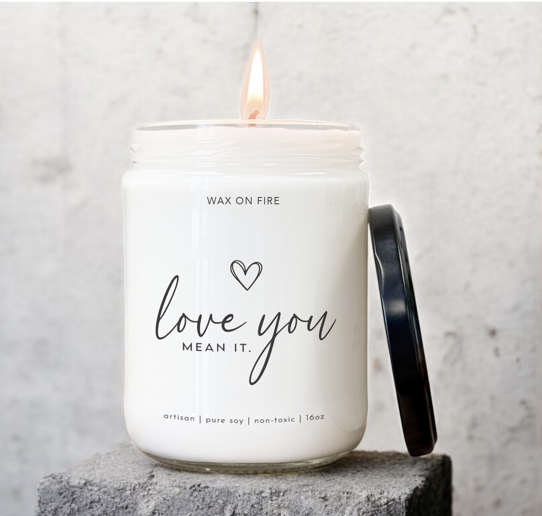 Hand-poured soy candle 'Love You Mean It' in glass jar, non-toxic, clean-burning, with black lid.